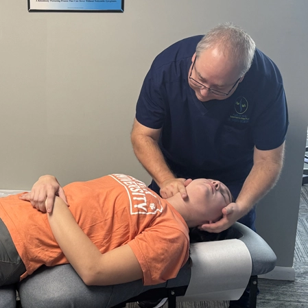 Dr. Scott Renshaw adjusting a patient who is wearing an orange shirt.